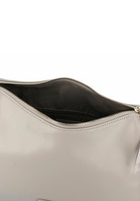 Tracolla in pelle grigia chiara con apertura superiore a zip, interno in tessuto nero e dettagli di cucitura discreti. Presenta un design sottile ed elegante.