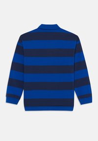 Πόλο μπλούζα με μακριά μανίκια και ευρείες οριζόντιες ναυτικές και βασιλικές μπλε ρίγες, εμφανιζόμενη από πίσω σε λευκό φόντο.