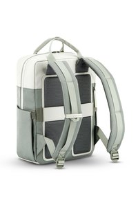 Mochila de tela gris con acentos blancos, correas acolchadas y detalles de malla. Cuenta con un bolsillo con cremallera y un logo en una correa frontal.