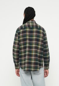 Grøn- og sortternet flannel skjorte med flerfarvede accenter, der har lange ærmer, krave med knaplukning og en afslappet pasform.