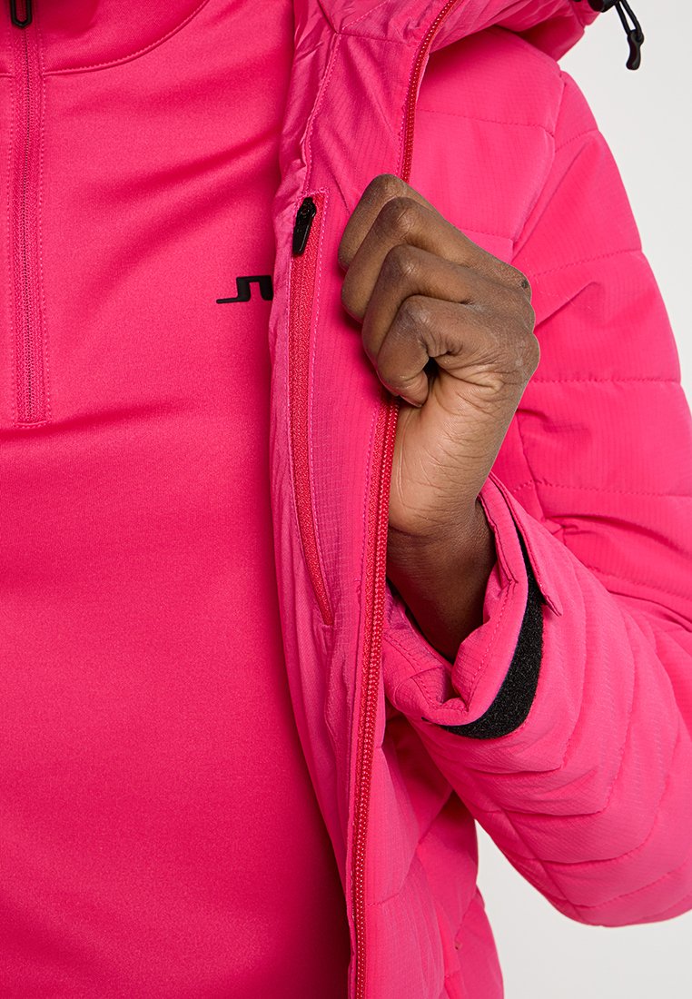 Helle rosa isolierte Jacke mit durchgehendem Reißverschluss, kontrastierender Innenauskleidung, strukturiertem Stoff und taillierter Passform.