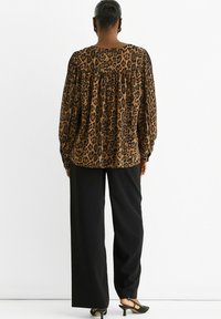 Brown and black leopard print blouse with long sleeves and a gathered back, paired with black wide-leg pants and black heeled sandals.