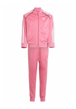 Rosa Trainingsanzug aus glattem Polyester. Mit einer Jacke mit Reißverschluss und weißen Streifen sowie passenden Hosen. Auffälliges adidas-Logo auf beiden Teilen.