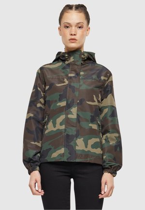 Chaqueta de camuflaje en tonos de verde y marrón, con capucha, cierre con cremallera en la parte delantera, puños elásticos y un ajuste relajado. Material ligero.
