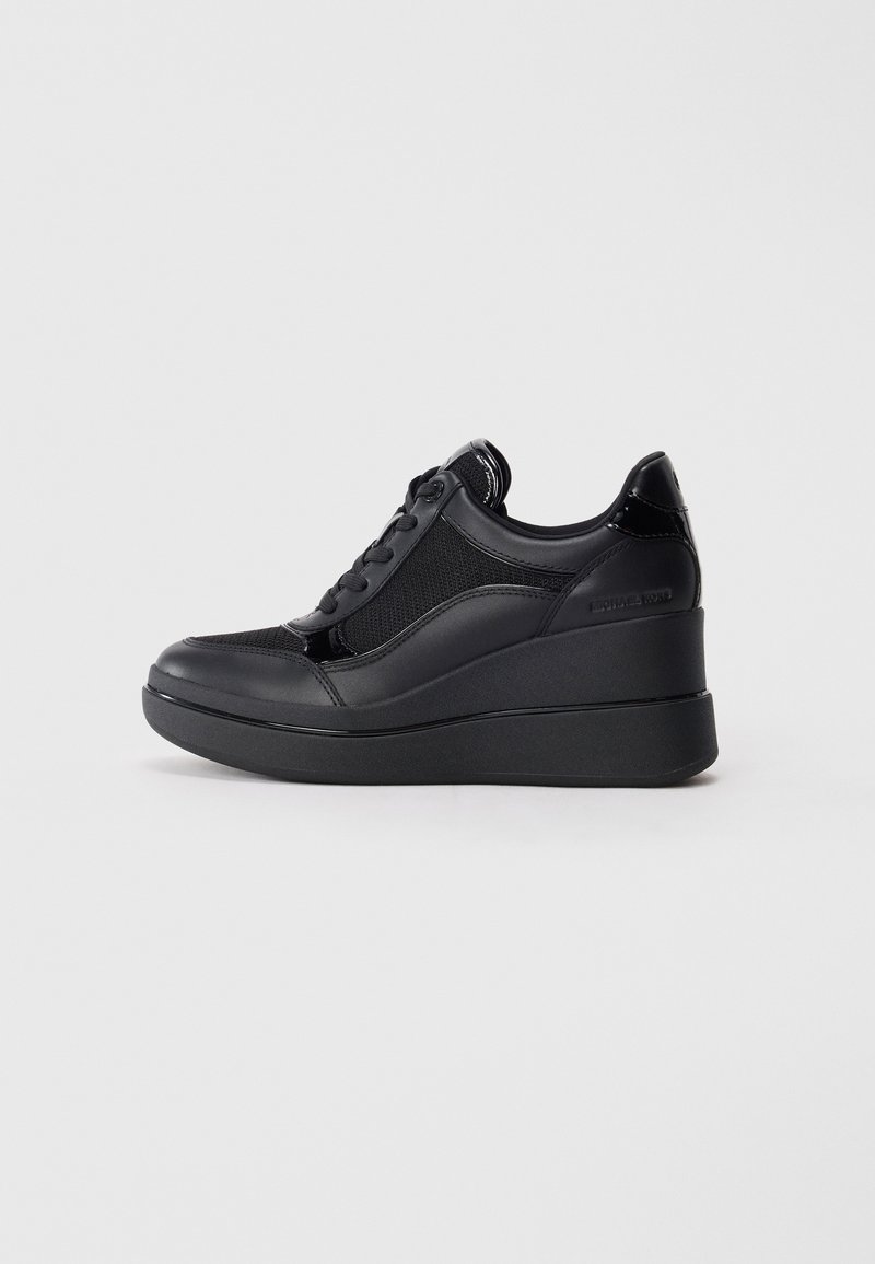 Sneaker nera con tomaia in rete testurizzata, dettagli in pelle lucida e suola a cuneo. Presenta lacci e un dettaglio laterale con marchio.