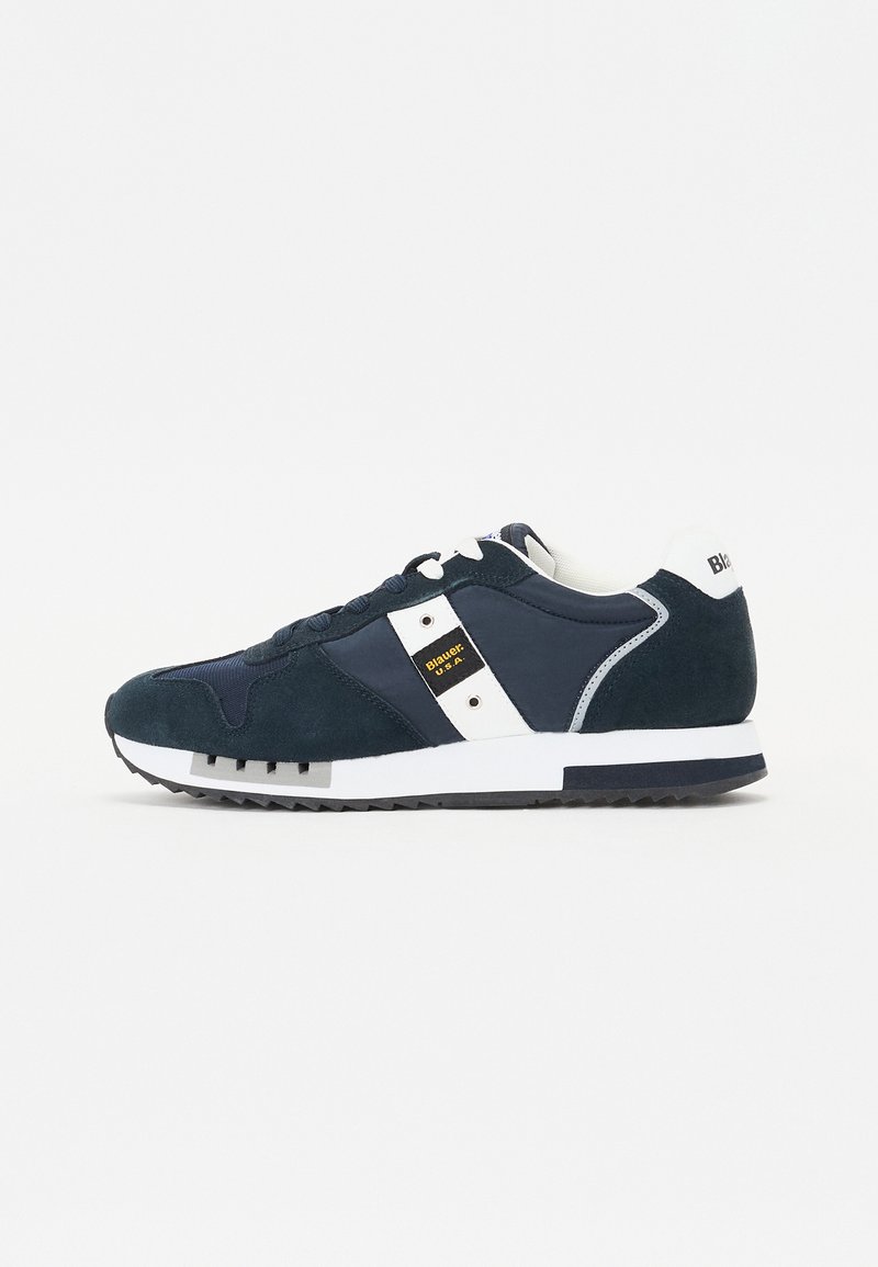 Dunkelblaue Wildleder-Sneaker verfügen über eine weiße Zwischensohle und Akzente, eine abgerundete Zehenpartie und eine strukturierte Gummisohle mit einem markanten Profil.