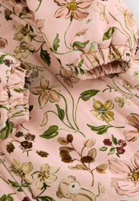 Õrnroosa tooniga lillemustriga kangas, millel on mitmesugused rohelised, pruunid ja kollased lilled ning lehed; tekstuuriga korduroos.