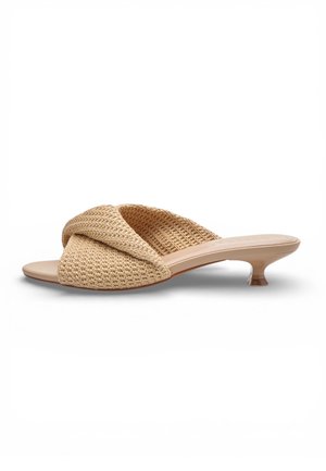 Mule aperto beige intrecciato con tacco basso a gattino e cinturini incrociati testurizzati, mostrato di profilo su sfondo bianco.