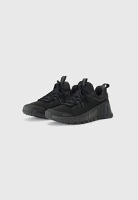 Scarpe sportive nere con tomaia in tessuto texturizzato, suola flessibile, stringhe ben visibili e dettaglio del logo sul lato. Design leggero e minimalista.