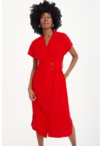 Rotes, kurzärmeliges Kleid mit Kragen, tailliertem Design und Knopfdetails. Der Stoff ist glatt mit einer fließenden Silhouette und mittellanger Schnittführung.
