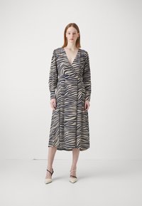 Pitkähihainen, vyötärölle sidottu mekko zebra-raidoilla, jossa on kermaista, laivastonsinistä ja vaaleaa väriä. Mekossa on runsaat hihat ja syvä V-pääkallo.