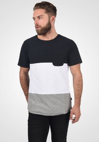 Camiseta a rayas en negro, blanco y gris con cuello redondo, mangas cortas y un bolsillo en el pecho. Confeccionada en tejido de mezcla de algodón.