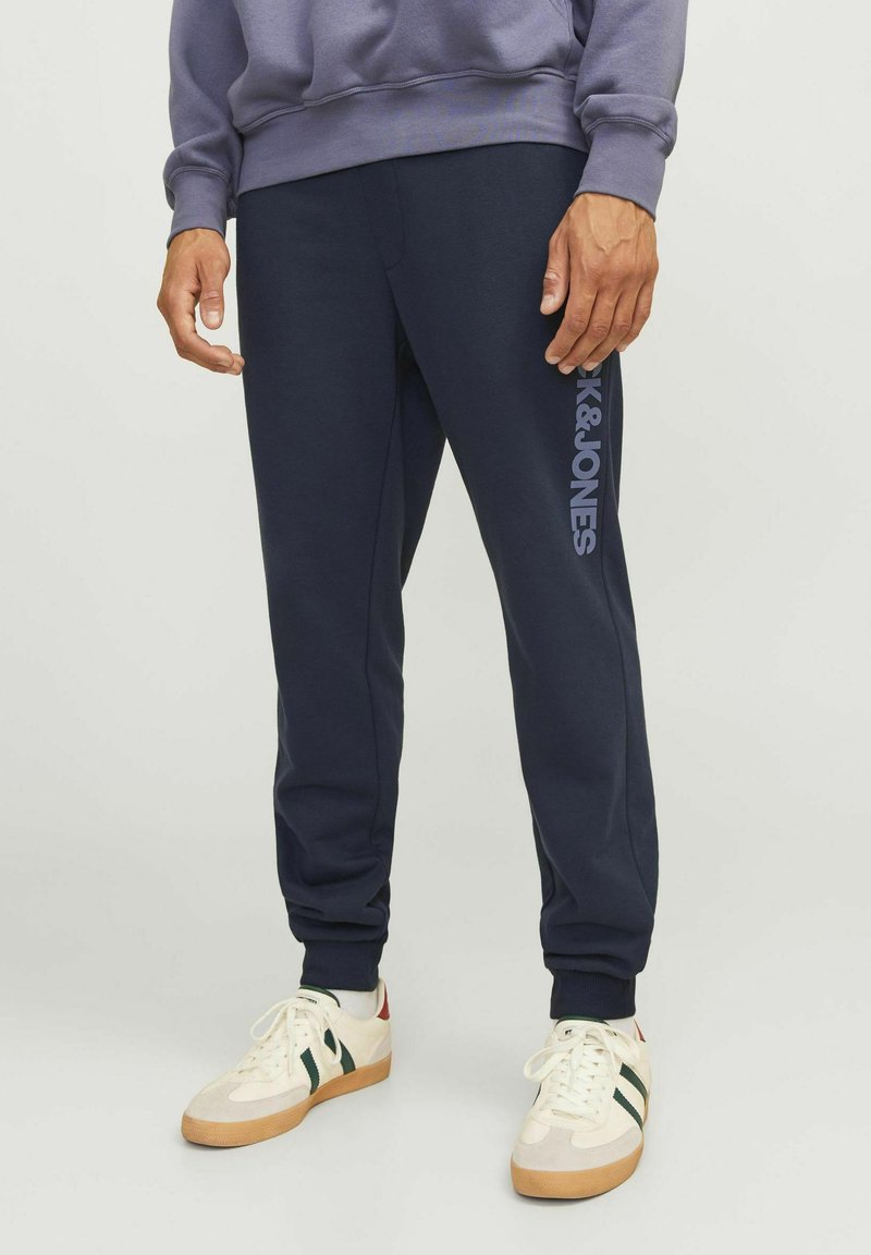 Pantalones de chándal azul marino con el logo de K&JONES en azul claro en el costado, con un diseño ajustado y puños de canalé en los tobillos.