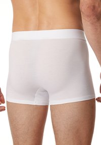 Boxers en coton blanc avec une douce taille élastique, présentant un design sans couture et une texture lisse, vus de l'arrière.