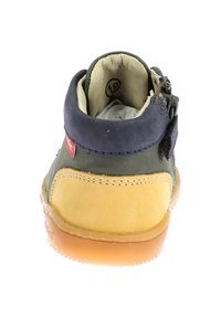 Botín infantil en ante verde y amarillo, con un cuello en ante azul, cremallera lateral y suela de goma. Etiqueta de tamaño visible en el interior.