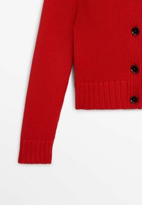 Röd stickad cardigan med lång ärm, ribbade muddar och fåll, med tre synliga svarta knappar framtill.