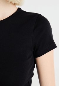 Svart kortärmad t-shirt med rund halsringning. Tillverkad av mjukt, stretchigt material med en slät yta och en kroppsnära design.