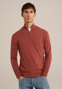 Pulover de culoare ruginie, cu mâneci lungi și guler cu jumătate de fermoar, fabricat din material moale. Design ajustat cu manșete și talie ribbate.