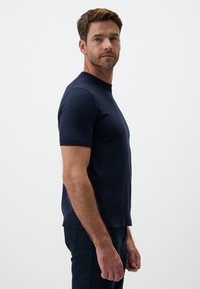 Granatowy, dziergany sweter z krótkim rękawem, z ribbowanym okrągłym dekoltem, w dopasowanym fasonie i gładkiej fakturze.