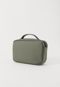 Pochette da viaggio compatta di colore verde oliva con manico nero e chiusura con zip su sfondo bianco.