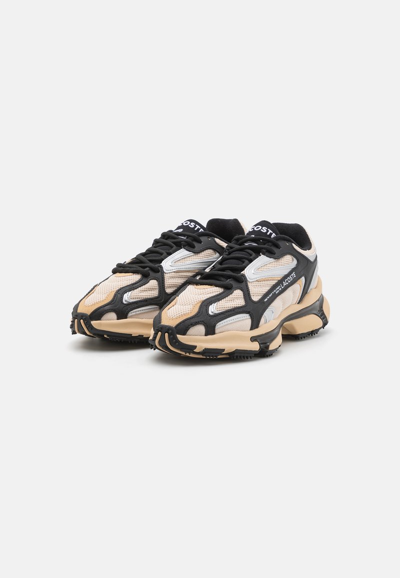 Zapatillas de malla y sintéticas con un diseño en beige y negro, detalles en plata, suelas gruesas y un sistema de cordones prominente.