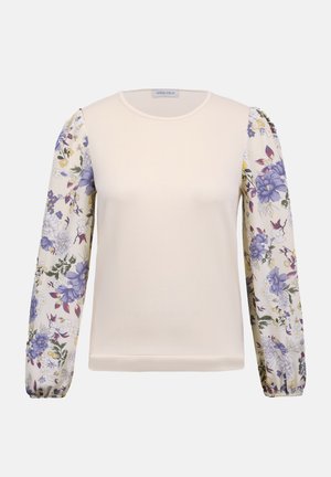 Κρεμ μπλούζα με στρογγυλή λαιμόκοψη και μακριά διάφανα μανίκια με μοτίβα από μοβ και κίτρινα λουλούδια.