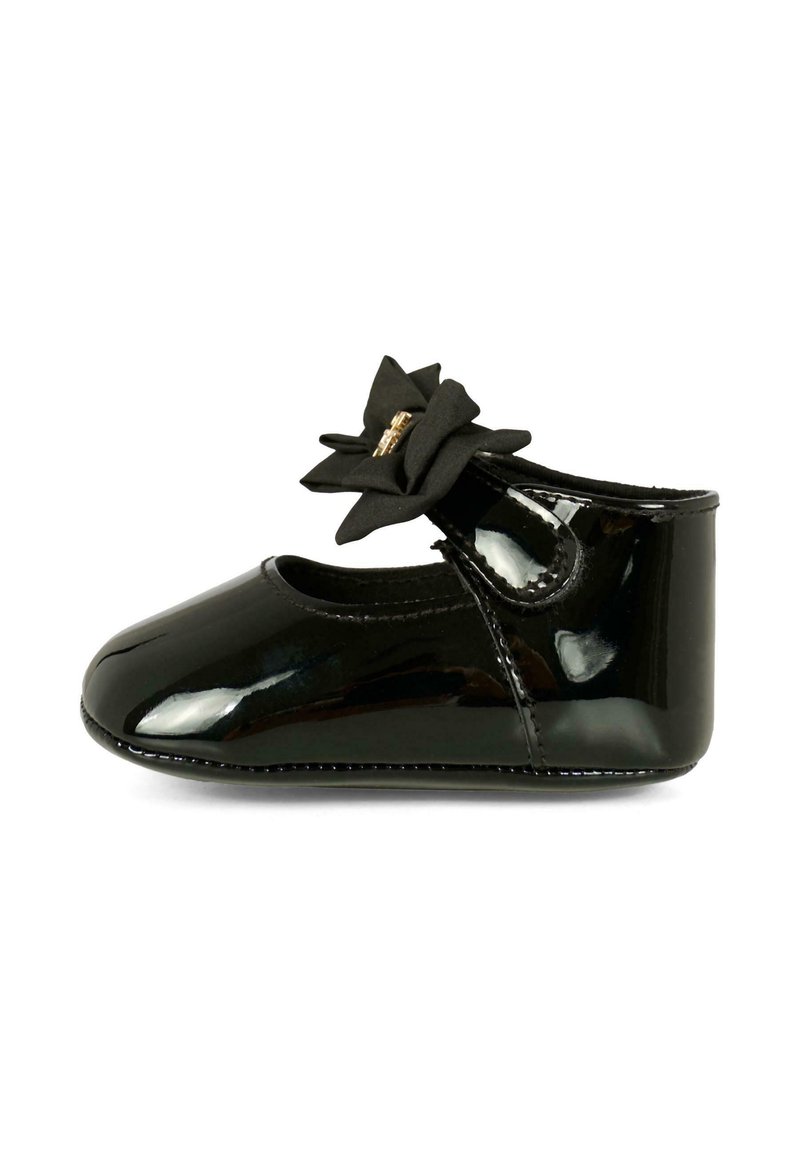 Scarpa in vernice nera con punta rotonda, cinturino alla caviglia e decorazione di un fiore nero. Superficie liscia e lucida.