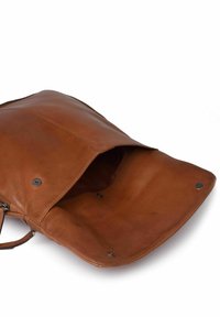 Bolso de cuero marrón con cierre de solapa, que presenta una textura suave y detalles metálicos. El interior es espacioso y sin forro.
