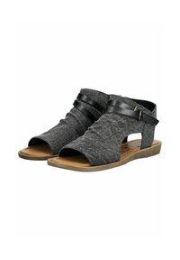 Sandalias de tela gris con dedos al aire, que cuentan con correas de cuero y suela plana. El diseño incluye cortes y tela texturizada.