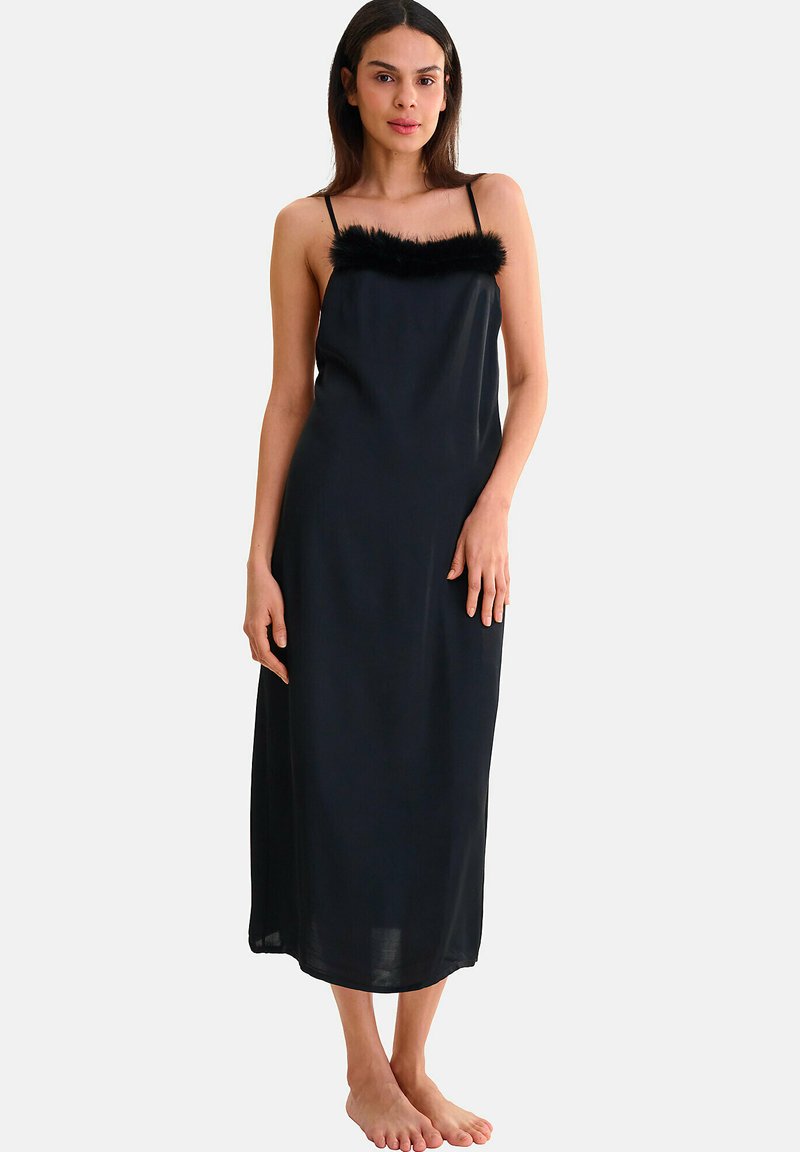 Robe nuisette noire avec des fines bretelles, un ourlet en fourrure noire autour de l'encolure et une silhouette fluide qui atteint le mi-mollet.