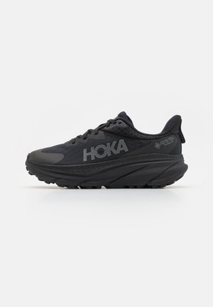 Pantofi de alergare negri cu un superior din plasă, accente texturate și branding HOKA. Au o talpă groasă și curbată, precum și Gore-Tex pentru rezistență la apă.