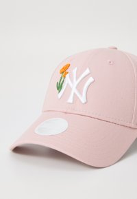 Rózsaszín baseball sapka fehér hímzett "NY" logóval és narancssárga virág díszítéssel, texturált anyagból készült, normál ívelt napellenzővel.