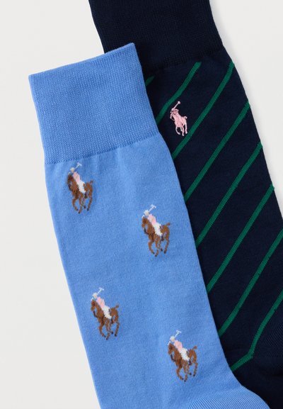 Ζευγάρι κάλτσες, μία γαλάζια με μοτίβα αλόγου και αναβάτη, μία σκούρα μπλε με πράσινες διαγώνιες ρίγες και ένα ροζ έμβλημα αλόγου και αναβάτη.
