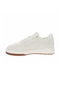 Zapatillas de ante blancas con una textura suave, suela de goma en marrón claro, con un diseño de caña baja y detalles de costura sutiles.