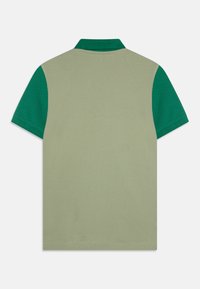 Īsām piedurknēm polo krekls ar gaiši zaļu ķermeni un tumši zaļu apkakli un piedurknēm. Izgatavots no elpojoša kokvilnas ar gludu tekstūru.