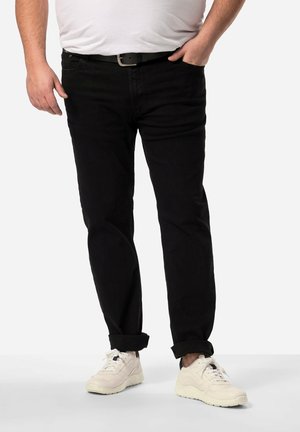 Schwarze Denim-Jeans mit geradem Schnitt, mittelhoher Taille und umgeschlagenem Saum, getragen mit weißen Sneakern und einem taillierten weißen T-Shirt.