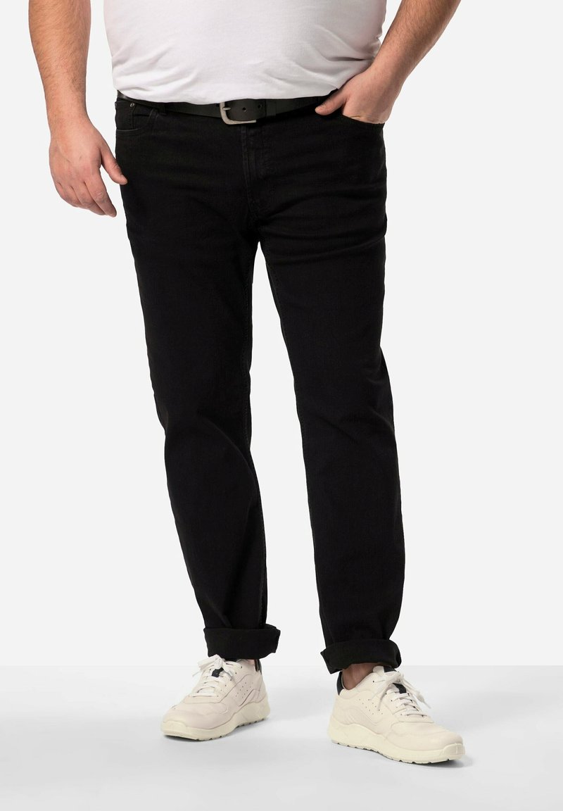 Svarta denimjeans med rak passform, med medelhög midja och uppvikta benslut, bärs med vita sneakers och en åtsittande vit t-shirt.