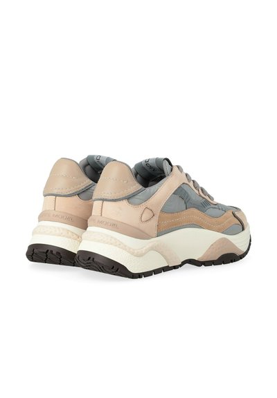 Une paire de baskets basses beiges et grises avec des semelles épaisses blanches et une semelle noire, inclinées pour montrer les vues arrière et latérale.