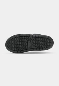 Suola di scarpa in gomma nera con una presa testurizzata caratterizzata da un motivo triangolare e un logo in rilievo. Bordo liscio e design arrotondato.