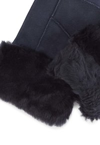 Matériau en daim noir avec un poignet en fourrure noire douce et pelucheuse, mettant en valeur une texture lisse et des coutures visibles le long des bords.