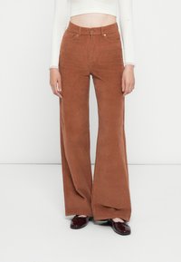 Bruine corduroy wijde broek met hoge taille, voorkeurszakken en een enkele knoopsluiting, met een gemarmerd oppervlak en rechte snit.