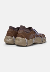 Brown mesh sneakers with a textured knit upper and a thick, speckled sole. Features blue laces and a snug, flexible design.