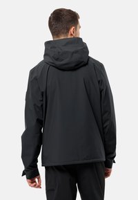 Veste noire imperméable avec capuche, dotée d'une coupe décontractée et de poignets élastiques, conçue pour une utilisation en extérieur. Dos sans couture pour un look épuré.
