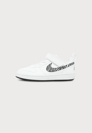 Λευκό sneaker χαμηλού ύψους με μαύρο και λευκό λογότυπο Nike σε ζεβρέ σχέδιο και κλείσιμο με αυτοκόλλητο velcro σε μονόχρωμο φόντο.
