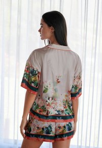 Pajama set w kwiatowym wzorze wykonany z miękkiego materiału, z krótkimi rękawami i szortami, z kontrastującymi paskami w zielonym i koralowym wykończeniu.