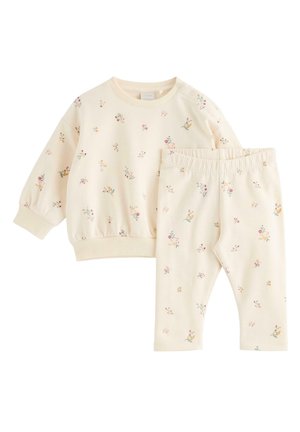 Completo per bambino color crema con maglia a manica lunga e pantaloni, decorato con piccoli motivi floreali multicolori.