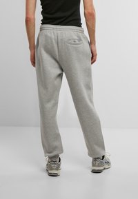 Gray sweatpants made of soft fabric with an elastic waistband and a back pocket, featuring a relaxed fit and tapered legs.