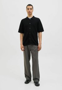 Black short-sleeve button-up shirt with a textured pattern, paired with gray wide-leg trousers and black shoes.