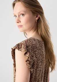 Top s leopardím vzorem vyrobený z lehké látky s volánovými rukávy; přírodní odstíny hnědé a béžové; jemná textura, stylové designové detaily.