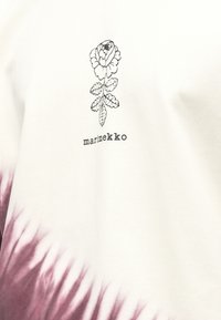 biały bawełniany t-shirt z czarnym kwiatowym nadrukiem i napisem „marimekko”. Dolna część przechodzi w głęboki bordowy wzór tie-dye.